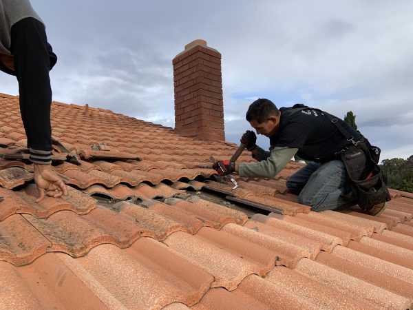 Crank roofer resetting clay tiles during a tile roof repair